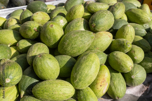A pile of fresh green Armenian cucumbers (snake melons) at a market stall.