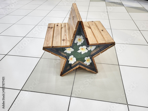 A star-shaped wooden bench filled with white artificial flowers.