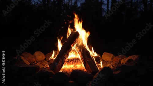 Burning campfire at dusk with flames and firewood