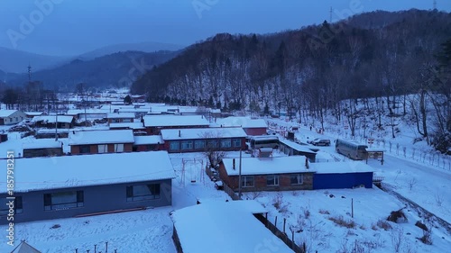The view of Snow Town village in Harbin, China, during the winter festival with a snowstorm, with snow clinging to the rooftops of houses.