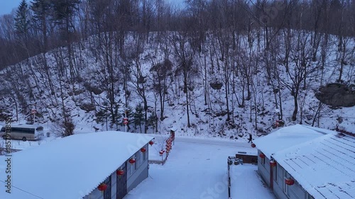 The view of Snow Town village in Harbin, China, during the winter festival with a snowstorm, with snow clinging to the rooftops of houses.
