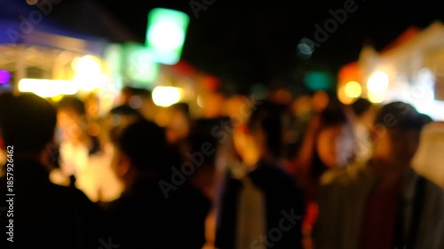 A group of people are standing in a dark alleyway. The scene is blurry and the people are not clearly visible. Scene is mysterious and somewhat ominous