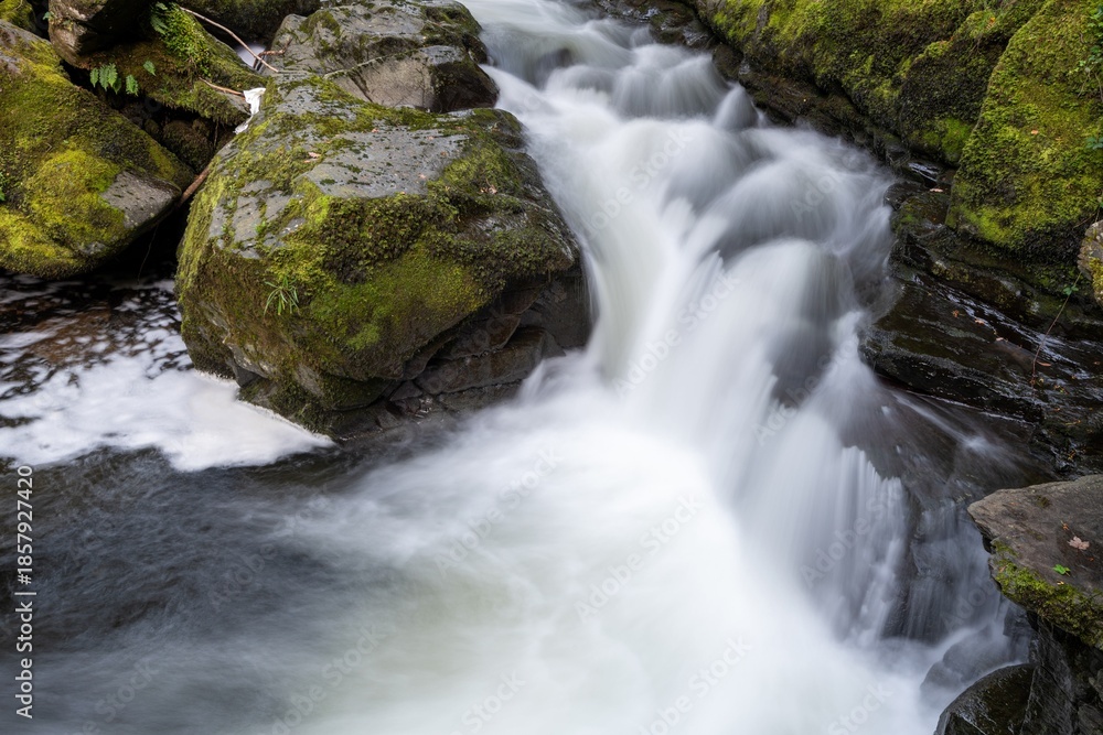Fototapeta premium Long exposure of a waterfall on the East Lyn river flowing through the woods at Watersmeet in Exmoor National Park