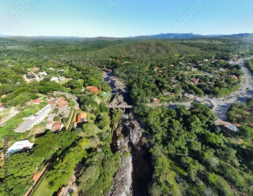 Wide angle drone photo over a bridge crossing Rio Cipó in Serra do Cipó, Brazil, showing the river flowing through rocky terrain surrounded by lush green vegetation and countryside landscape