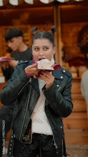 Enthusiastic woman takes playful bite of pastry during lively outdoor event