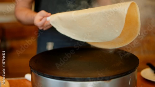 Experienced chef skillfully uses wooden spatula to turn pancake outside