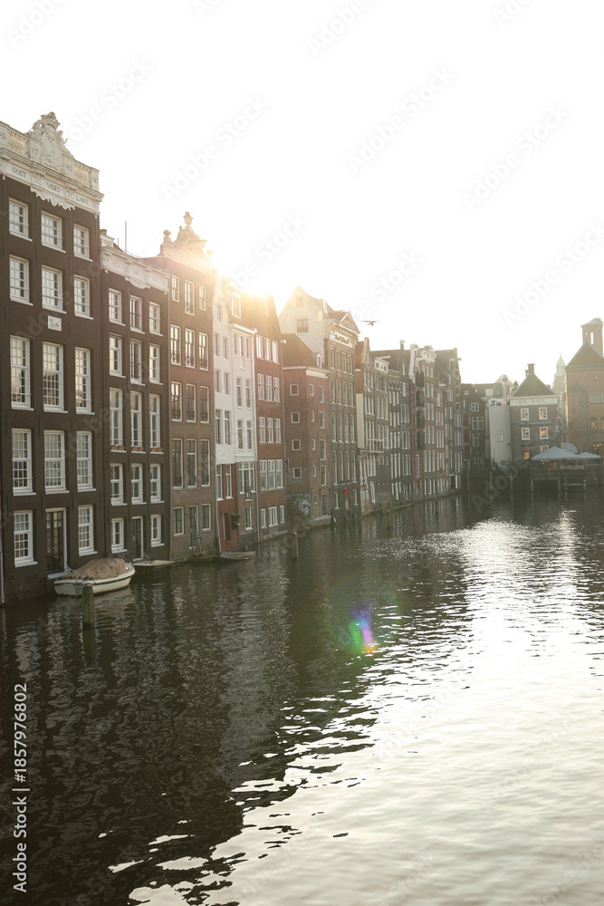 Fototapeta premium Amsterdam canals at sunset with warm light and reflections.