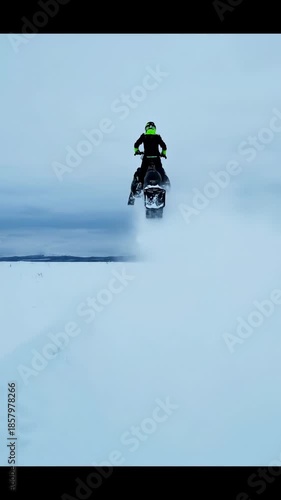 Snowmobile Rider Speeds Across Snowy Landscape, Winter Adventure, Cold Weather.