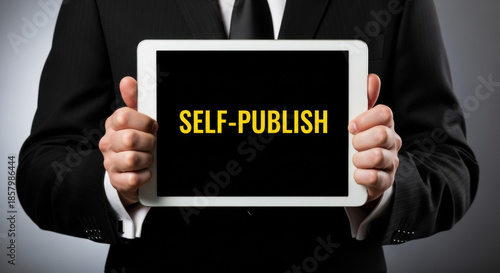 Wallpaper Mural A man in a dark suit presents a digital tablet displaying the text 'Self-Publish' against a gray background, highlighting entrepreneurship and digital content creation. Torontodigital.ca