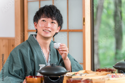 Fotografija Young Asian man enjoying kaiseki cuisine at a ryokan (room dining, kaiseki cuisi