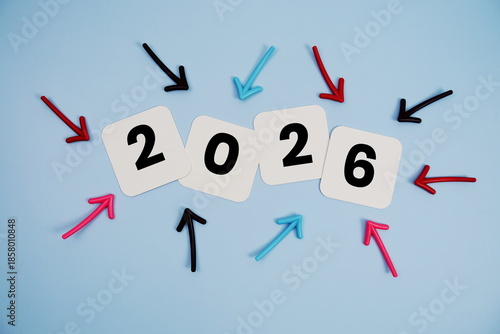 Happy New Year 2026 on cards with colorful arrows pointing toward it on blue background