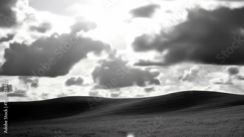 Dramatic monochrome landscape with rolling hills and cloudscape under sunlight