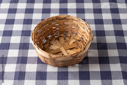 Empty rustic wicker basket on blue and white checkered tablecloth