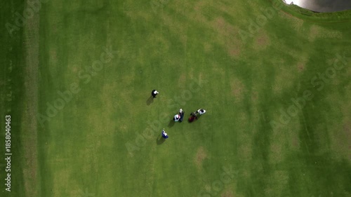 Aerial Drone Shot of People Playing Golf on Green Course, Aerial drone view of people playing golf on a well-maintained green golf course.