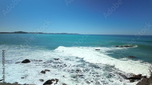 Waves crashing on rocks in turquoise ocean bay