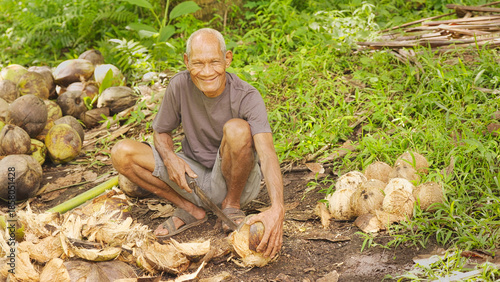 Obraz na płótnie Portrait, old man indonesian farmer smiling, looking at camera, on coconut farm