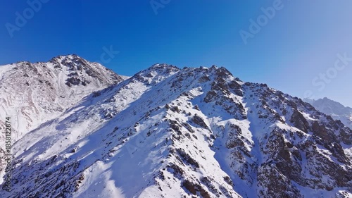 Aerial view captures majestic snow-covered mountains in Kyrgyzstan during winter. Arc camera movement.