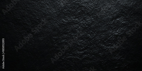A dark textured background of black slate stone with subtle variations in tone and minimal visibility
