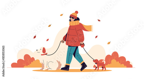 Woman in warm winter clothes walking two dogs in a park with falling orange leaves and colorful autumn bushes.
