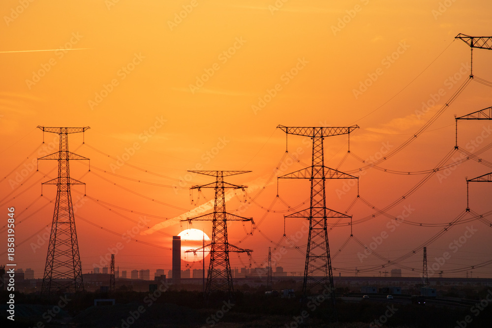Obraz premium High Voltage Power Lines at Sunset with City Skyline