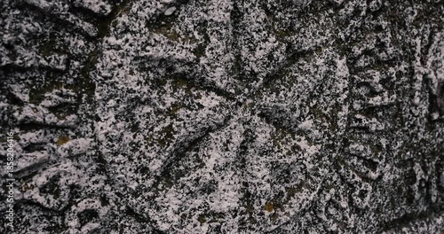Shallow depth of field (selective focus) details with inscriptions and texture of an old orthodox christian stone cross.
