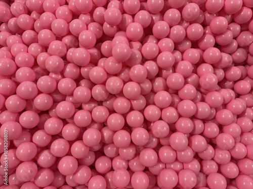Pink plastic balls densely packed forming glossy round texture with playful abstract pattern and cheerful vibrant mood
