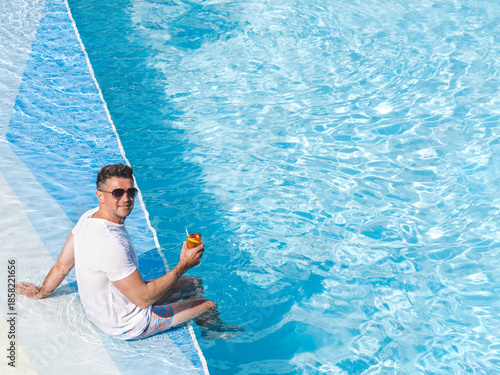 Handsome man relaxing with a drink by the cruise ship pool on a sunny, clear morning. Top view. Vacation and travel concept. Chill lifestyle, luxury travel. Perfect for holiday and travel themes