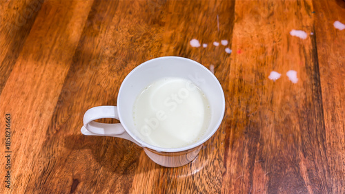 cup of fresh milk on wooden table top view
