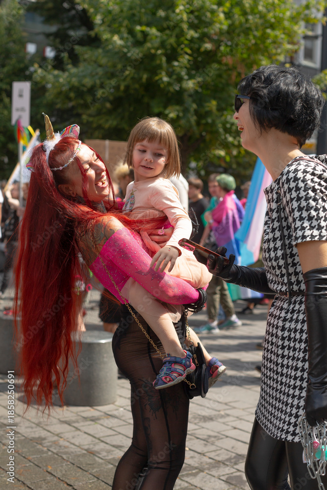 Fototapeta premium candid street greeting between performer and friend, child held in arms, warm exchange and sunny trees