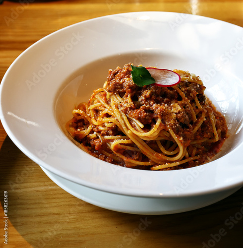 spaghetti bolognese on a white plate in a restaurant
