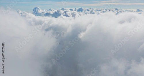 Atmospheric aerial view revealing soft fluffy cumulus and stratocumulus clouds, blue horizon and serene, ethereal sky perfect for travel or nature themes. Natural background, drone flight