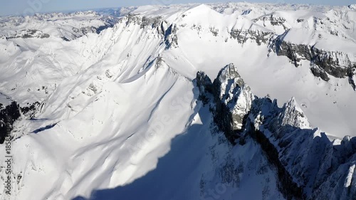 Aerial winter view of the Martinsloch and surrounding snow covered alpine mountains under clear blue sky