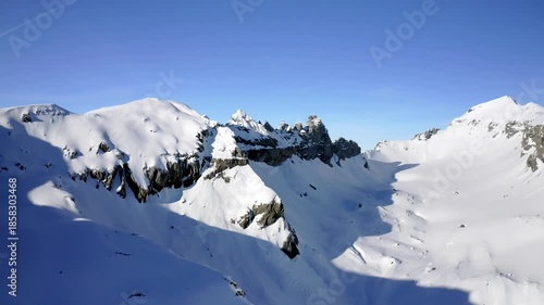 Aerial winter view of the Martinsloch and surrounding snow covered alpine mountains under clear blue sky