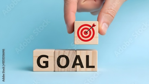 Hand placing target icon block completing the word goal with wooden cubes