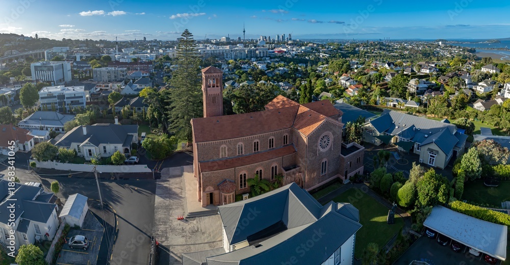 Fototapeta premium Aerial view of a church in Remuera, Auckland, New Zealand, with the city skyline in the background. The photo showcases the architecture and urban landscape.