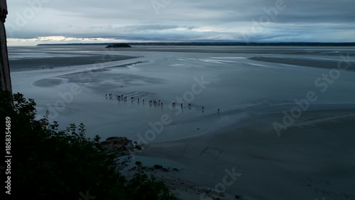 Mont saint-Michel, 08-24-2024. People walking on the bay during low tide. Slow motion. Panning 4K