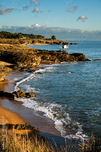 Beautiful coastal landscape, rocks, ocean, sand, and a fishing hut. Holiday background of the French coast on the Atlantic Ocean during sunset.