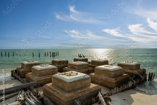 Historic Cape San Blas lighthouse site with pelicans perched along the shore, sandy dunes, and calm Gulf waters - weathered coastal architecture meets native wildlife