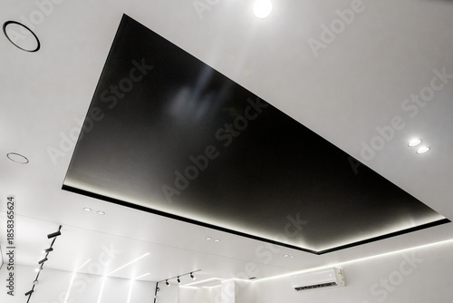 A minimalist interior photo of a ceiling with a contrasting black niche and modern LED lighting in a black and white style.
