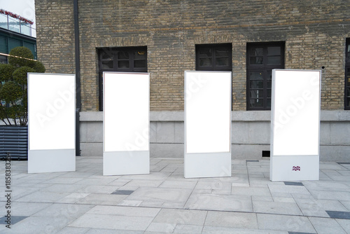 Four blank white outdoor advertising stand or sandwich boards mock up template placed by an indoor building