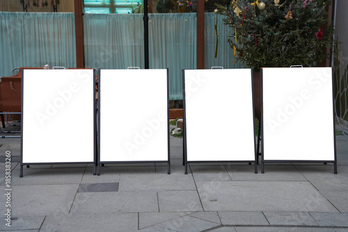 Four blank white outdoor advertising stand or sandwich boards mock up template placed by an indoor building