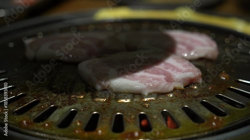 Grilled meat on a charcoal grill pan at Korean BBQ restaurant.