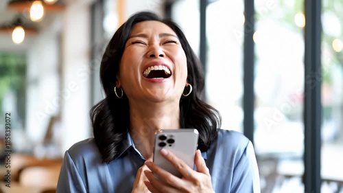 Asian Woman Laughing Hysterically While Looking at Her Smartphone Screen