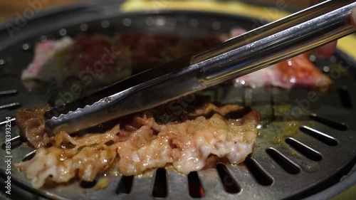 Grilled meat on a charcoal grill pan at Korean BBQ restaurant.