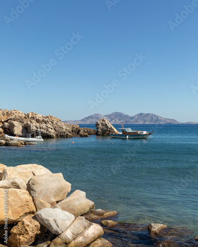 Peaceful rocky cove with clear blue water on Ikaria island, Greece. Natural Mediterranean coastline, calm atmosphere and summer travel destination.