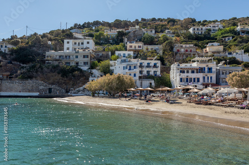 Turquoise water and sandy beach in the seaside village of Therma on Ikaria island, Greece. Traditional houses along the coast, summer atmosphere and Mediterranean travel destination.