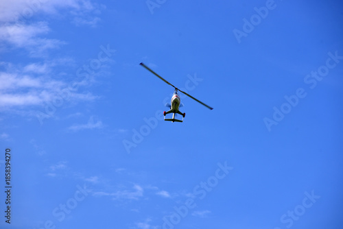 Gyrocopter flying with background of blue sky