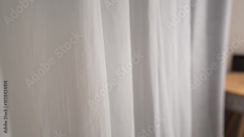 Sheer white curtain gently waving by breeze from open window. Concept of room ventilation and fresh air circulation.