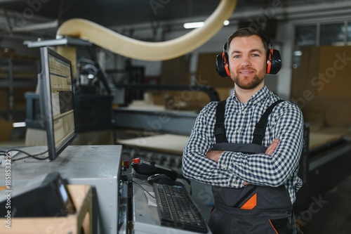 Foto Furniture maker posing with arms crossed in front of cnc machine