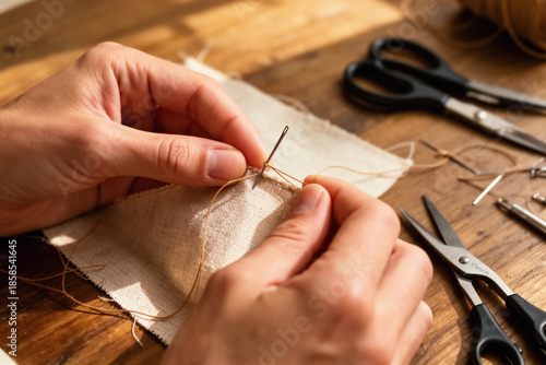 Hands sewing fabric on wooden craft table.